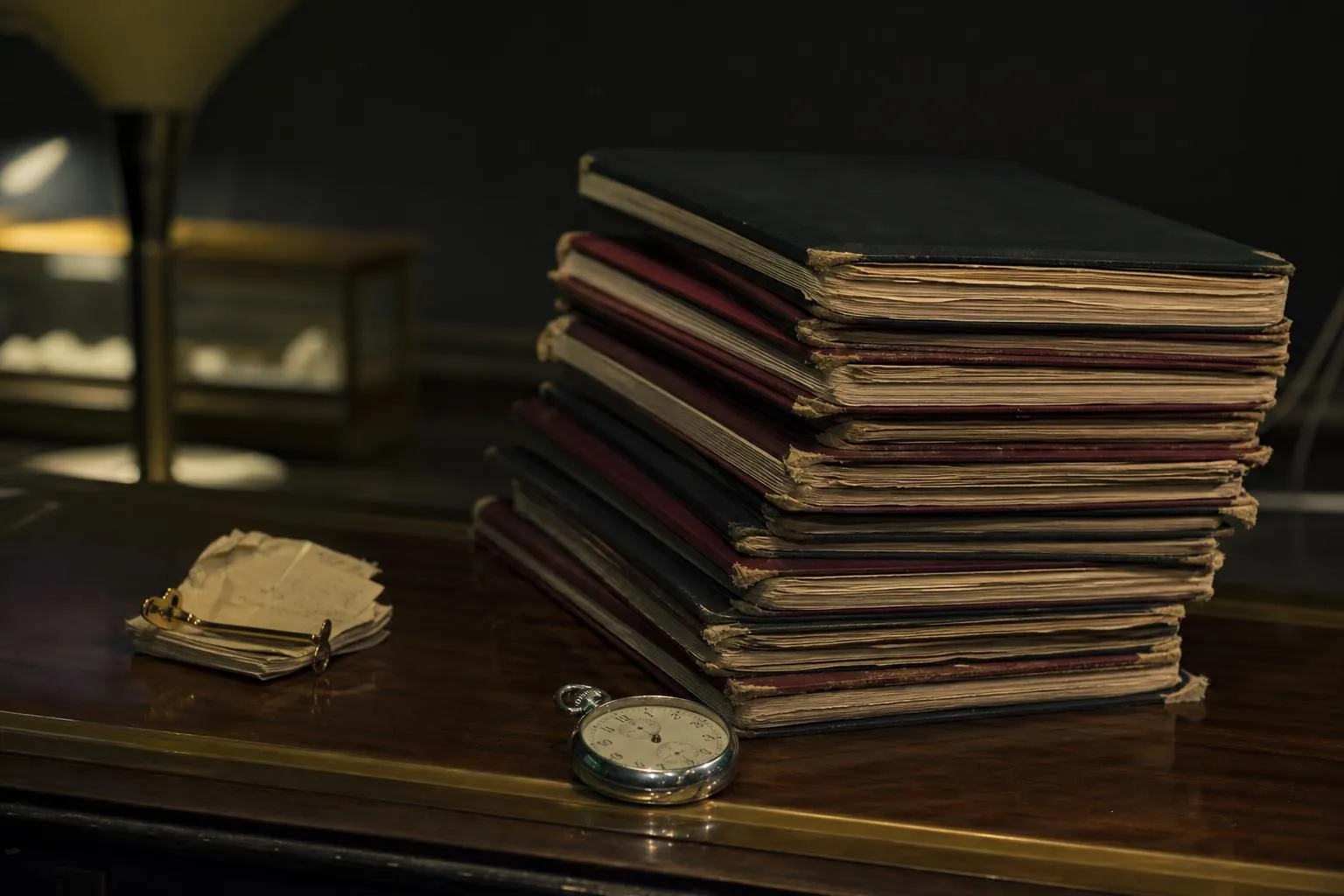 Pile de cahiers de comptoir usés posée près d’un chronomètre mécanique et d’un liasse de tickets sur un comptoir de bois